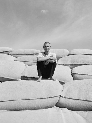 A black and white image of e4444e, crouching on a tier of rocks