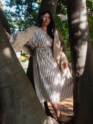 A woman poses against a tree.