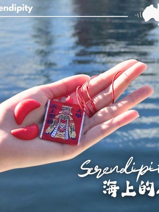 A lady holds onto a red Mazu, the Taoist ocean goddess as she stands in front of a calm waterbody.