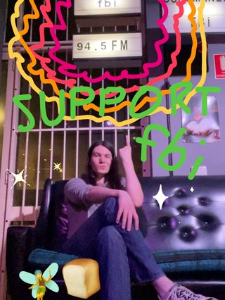 Jim sitting on a couch at fbi radio HQ. They are pointing to a sign above their head which says "fbi 94.5FM". The image has been decorated with colourful squiggles, sparkles, and a handwritten message saying "SUPPORT fbi".