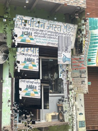 An image of a hi fi repair store taken in New Dlhi but the image has been pixelated and distorted to create glitchy and dragged effect