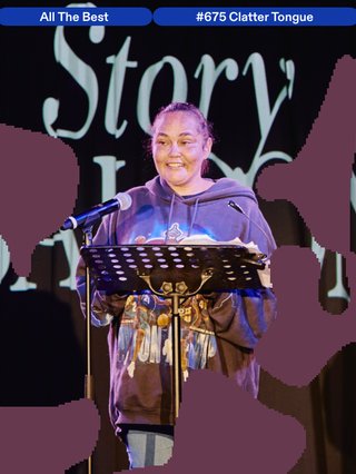 A picture of a person doing live reading on a stage in-font of a lectern as part of the "Vanguard in 2025 for StorySALOON."