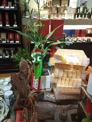 an illustration of a pickle with a santa hat on placed on a bamboo as an installation at a tea store