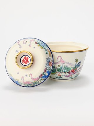 a ceramic vessel with the lid off and leaning against it. There is colourful illustrations on the vessel.