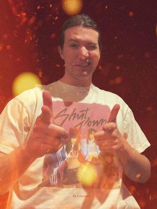 Jim throwing up finger guns. They have been edited in front of a dark background surrounded by flames.