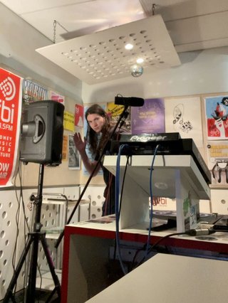 Jim on the other side of the fbi studio, slightly obscured by desks, speakers and microphones.