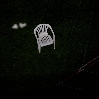 depiction of a white monobloc chair, on a grassy backdrop