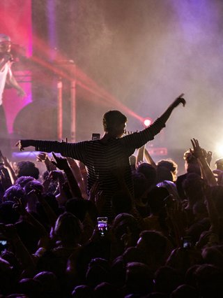 Rejjie Snow performs to a crowd with one person lifted into the air