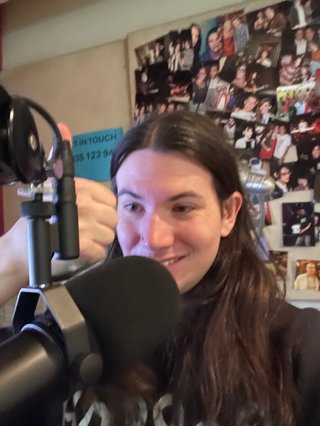 A slightly blurry selfie of Jim in the studio, holding a thumbs up pose in front of the microphone.