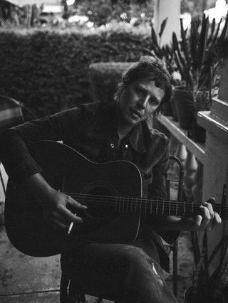 Gold Star. Seated man playing an acoustic guitar