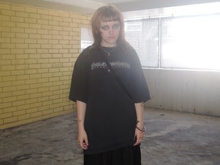 Artist Annabelle Scobie standing in the corner of an underground parking garage, wearing all black