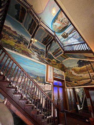 a timber stairway surrounded by murals of the bush in broken hill’s palace hotel