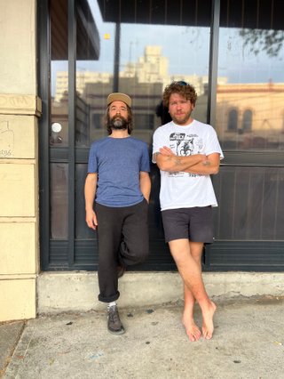 Ricky Albeck + Violinist Tom on the street leaning against the front window of the fbi station