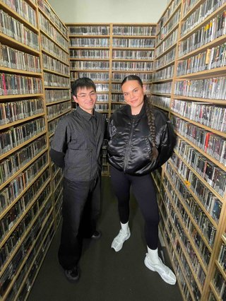Matt and Mi-Kaisha wear all black and pose in the music library