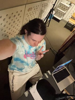 A selfie taken from above of Jim in the studio looking ahead holding up a peace sign. They look really cute in this picture.