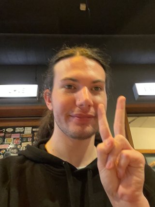 A blurry selfie of Jim holding up a peace sign and looking generally a bit crusty.