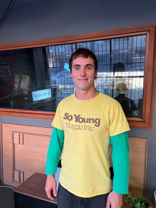 Louis Parsons from Floodlights standing in the fbi studio. He smiles and is wearing a yellow and green shirt