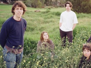 the five members of desire path sit or stand in a grassy field. they look peaceful and content