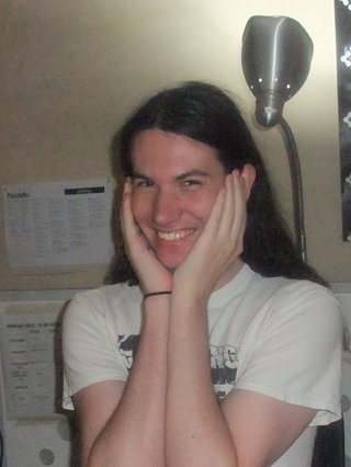 Jim Kretschmer in the studio with their hands cupping their face and smiling at the camera