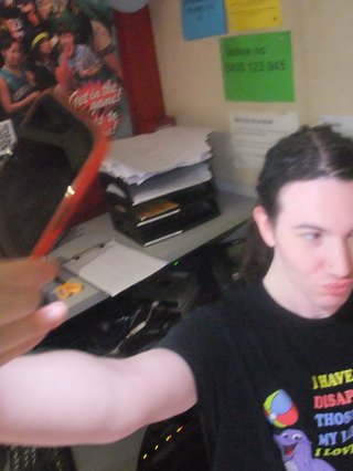 Jim Krestchmer is posing with their iPhone with the flash on pointed at their face as though they are taking a photo.