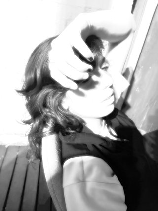 An overexposed, black and white profile of Kate, shot from the side. She is covering her forehead with her hand