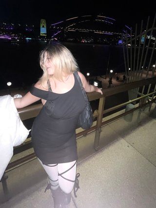 blonde woman posing in front of Harbour Bridge at night