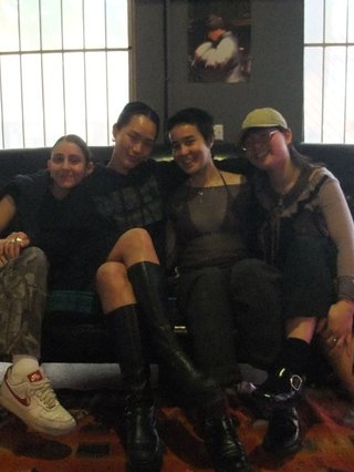 Aysenur, Yvonne, Alicia and Janey sit on the fbi couch close to each other and smiling
