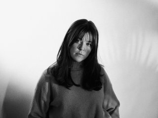 A black and white image of Sarah Levins, head slightly tiled with a pensive look on her safe