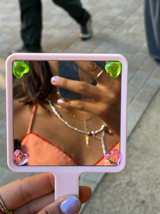girl taking a mirror selfie with a pink hand held mirror with love heart jewels on it