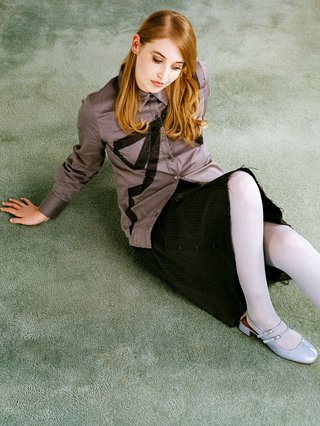 Girl with long hair is sitting back on the ground comfortably