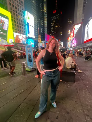 Woman standing in NYC Times Square, looking up and smiling.