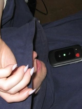 a hand with manicured nails on top of a navy hood covering a face facing a closed flip phone