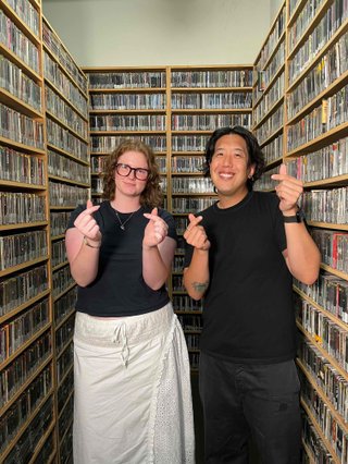 Kate and Harry throwing up finger hearts in the music library