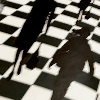 Two silhouettes of figures carrying bags, against a checkerboard background. The image is tilted slightly