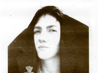 A slightly sepia tinged, black and white portrait of Solo Career. She is looking at the camera with narrowed eyes, and has a blazer sitting on top of her head.