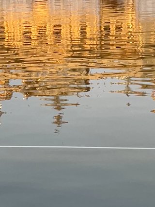 An image of a reflection. The water ripples at sunset with an upside view of the Golden Temple, Amristar