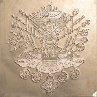 a champagne gold crest of arms, with arabic inscriptions