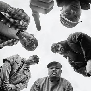 The album cover is a black and white photo of the five members of SPEED. The camera is positioned below them, and they are all looking down at it. The lead singer is holding up his finger in a number 1.