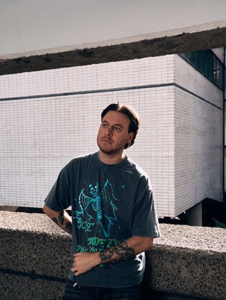 Man with beard leans on wall in the sun