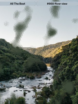 A sunset in the distance near a bushy and hilly landscape with a river flowing inbetween.