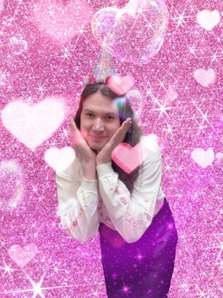 Jim posing sweetly with a birthday hat on their head. They are edited in front of a sparkly pink background with hearts and bubbles layered on top.