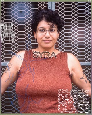 Syra posing - looking front on into the camera, wearing a brown/burgandy singlet