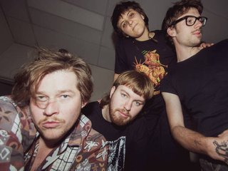 Image of Problem Green, in a dimly lit room with their faces being lit up.