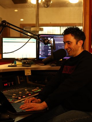 A happy presenter being trained in a professional radio studio.
