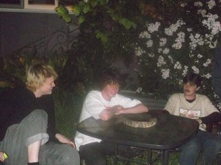 Four people sit around an outdoor table in low light.