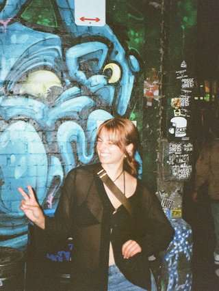 izzy is posed with peace sign in front of graffiti wall