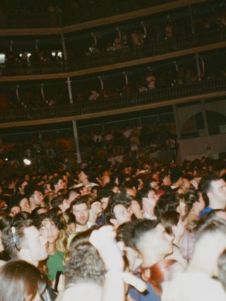 crowd at a concert venue with flash on and crowd facing towards the stage