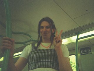 Jim Kretschmer in a really cute outfit with cute braids, standing on a train holding up a peace sign.