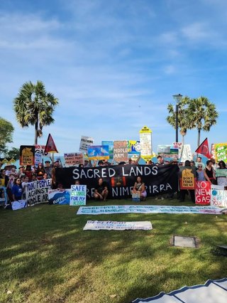 Protestors are on a lawn and the sky is blue - they are at Lee Point holding various signs to save it from destruction