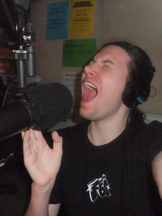 Jim with headphones on screaming into the microphone in the fbi studio.